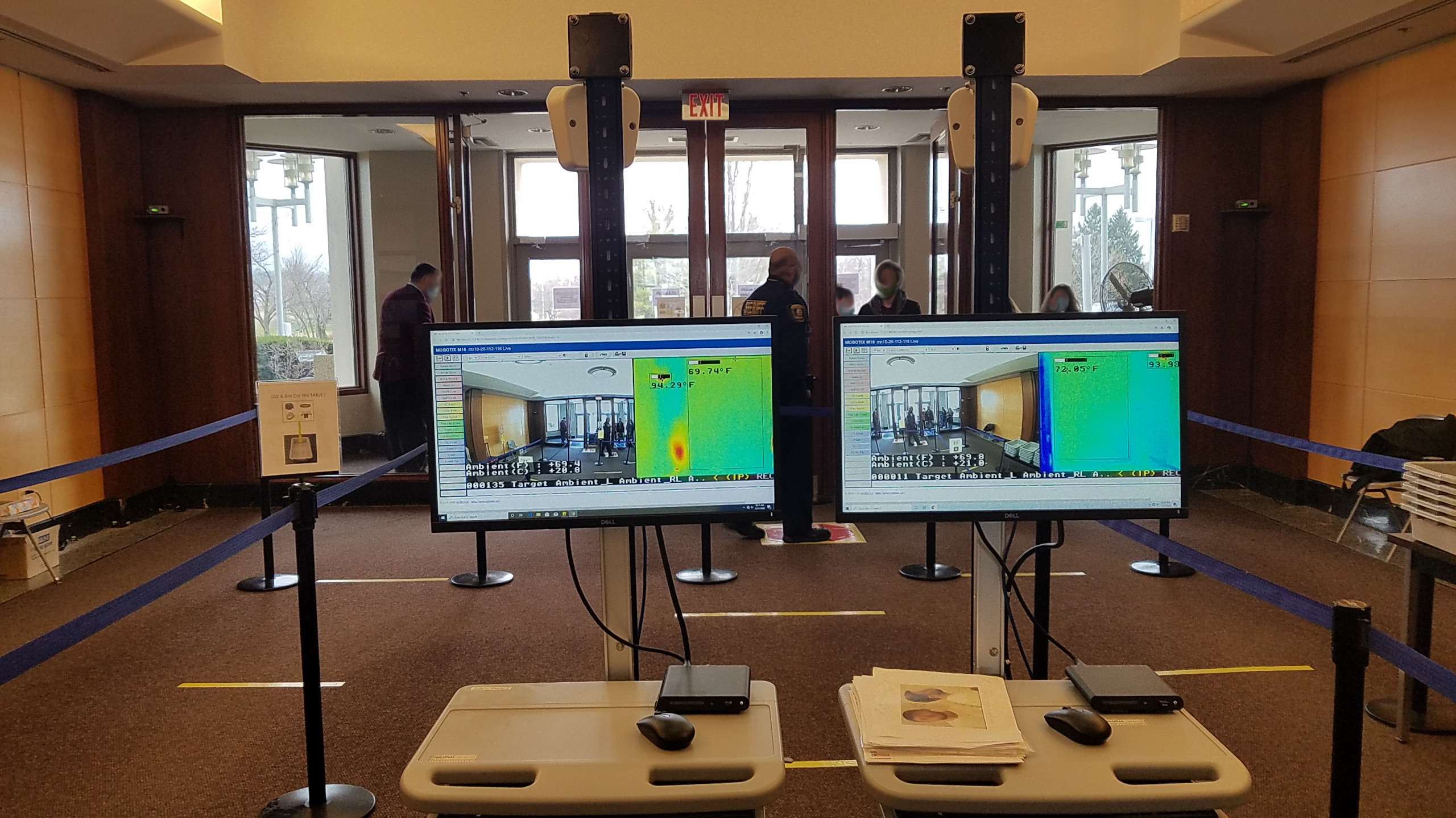 Security walk through with screens displaying thermal camera temperature readings and video surveillance